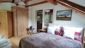 A bedroom with a large bed, a wardrobe, a small table, and a painting on the wall. - Stylishly furnished apartment in Rathmannsdorf in the Zauketal, allergy sufferers (Rathmannsdorf)