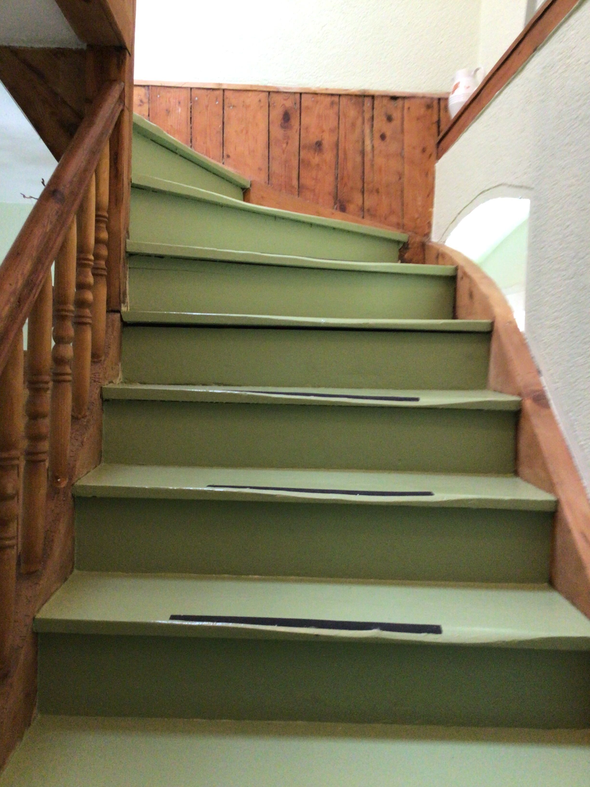 Un escalier en bois avec des marches vertes et une rampe en bois.