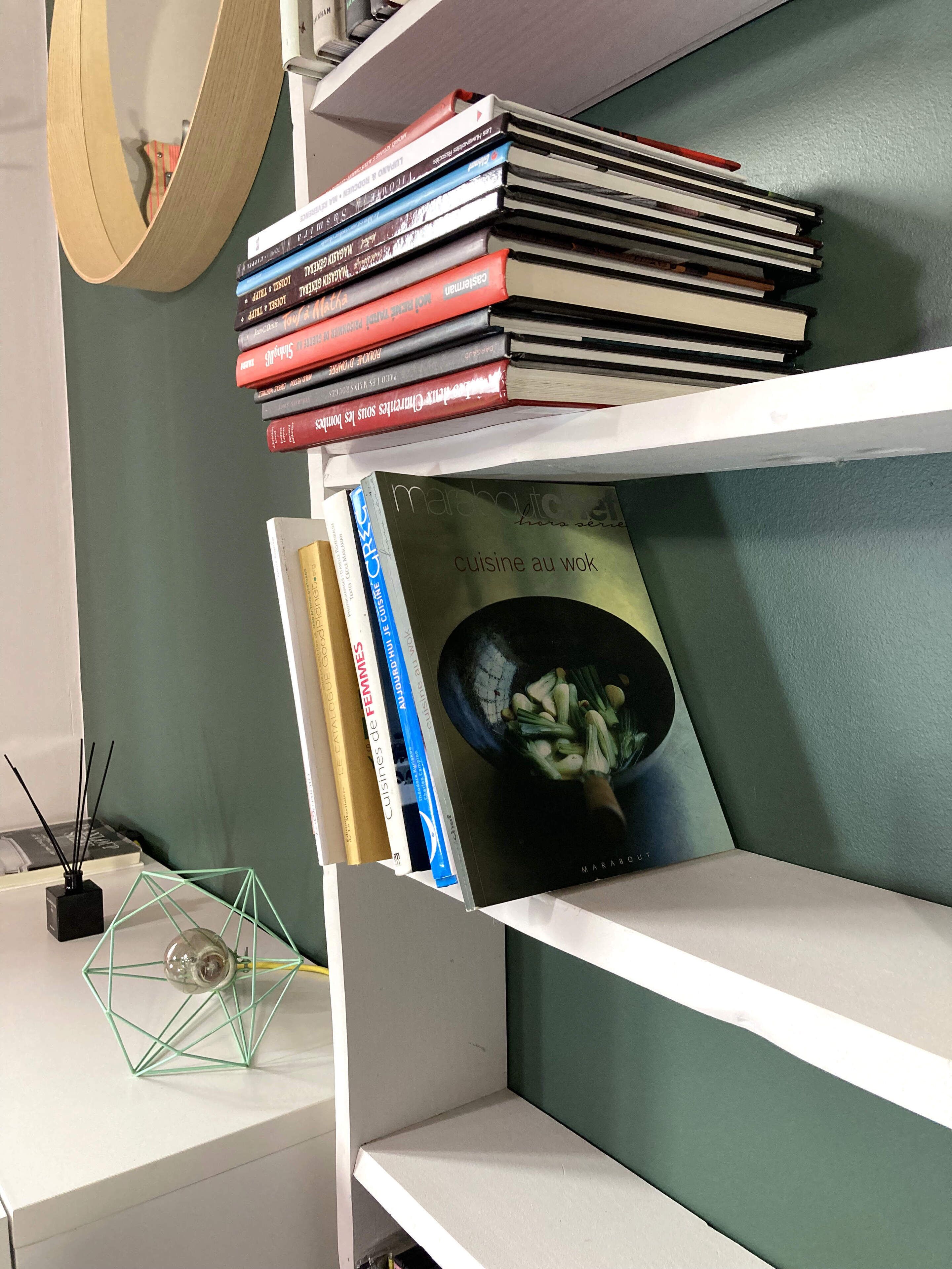 Une bibliothèque remplie de divers ouvrages, dont un livre intitulé « Marabout Cuisine au wok », qui est bien visible.
