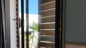 A modern interior with a sliding glass door leading to an outdoor area, a light-colored floor, and a partial view of a room with a dark-colored cabinet. - ☼ La Siesta ☼ Character house with garden and terraces ☼ (La Rochelle)