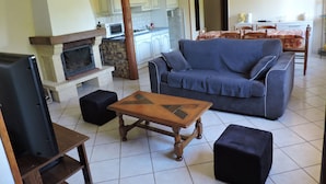 A living room with a fireplace, sofa, coffee table, and television. - Rental cottage in renovated farm (Arrentès-De-Corcieux)