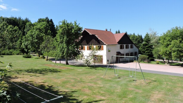 A house with a red roof, surrounded by a grassy lawn and trees. - Rental cottage in renovated farm (Arrentès-De-Corcieux)