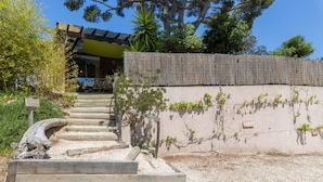 Un escalier menant à un bâtiment entouré d’une clôture en bambou et sur lequel est apposée une pancarte indiquant un espace de stationnement.