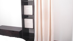 Une chambre à coucher avec un lit, une armoire et un rideau.