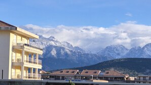 A hotel with multiple balconies, a mountain backdrop, and a clear sky. - CALVI T2 terrace for 4. Close to beaches, the city centre and all facilities (Calvi)