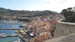 A coastal town with a marina, buildings with red-tiled roofs, and a mountainous backdrop. - CALVI T2 terrace for 4. Close to beaches, the city centre and all facilities (Calvi)