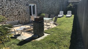 A stone building with a patio area featuring a table and chairs, a small garden, and a wooden fence. - House *** in Mont Saint Michel bay for 2 to 6 people  (Saint-Broladre)