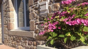 A stone building with a window and a concrete planter with pink flowers. - House *** in Mont Saint Michel bay for 2 to 6 people  (Saint-Broladre)