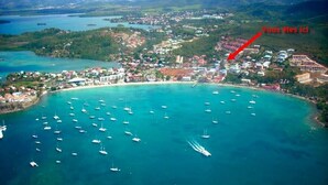 An aerial view of a coastal town with a beach, numerous boats, and a red arrow pointing to a specific location. - RESIDENCE VERY CALM  (Anse mitan)