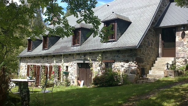 A stone house with a steeply pitched roof, multiple windows, and a stone staircase leading to the entrance. - Old farmhouse restored warm decoration comfortable on a 3ha plot (Saint-Donat)