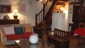A cozy living room with a sofa, a coffee table, a wooden bench, and a staircase. - Old farmhouse restored warm decoration comfortable on a 3ha plot (Saint-Donat)