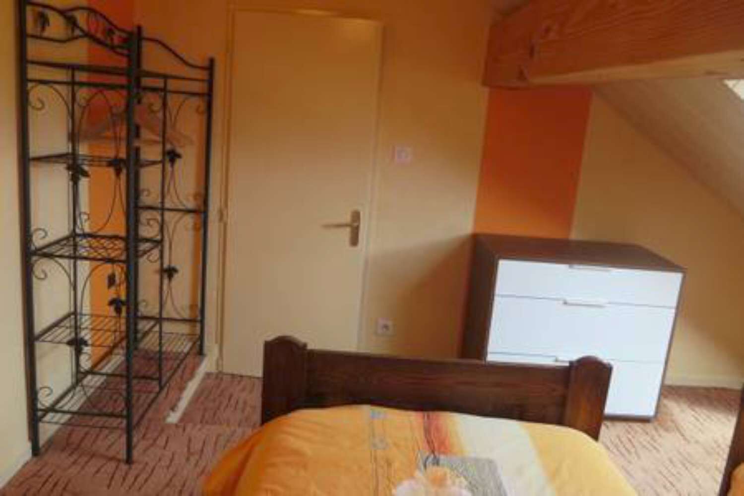 A bedroom with a bed, a wardrobe, and a metal shelf unit.