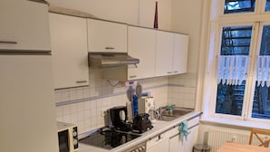 A kitchen with white cabinets, a stove, a sink, and a window with lace curtains. - beautiful apartment in good location with well connection to all landmarks  (Hamburg)