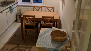 A small kitchen with a dining table, chairs, a window with lace curtains, and a radiator. - beautiful apartment in good location with well connection to all landmarks  (Hamburg)