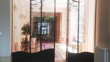 An entrance with a decorative metal gate leading to a room with a tiled floor and a potted plant.