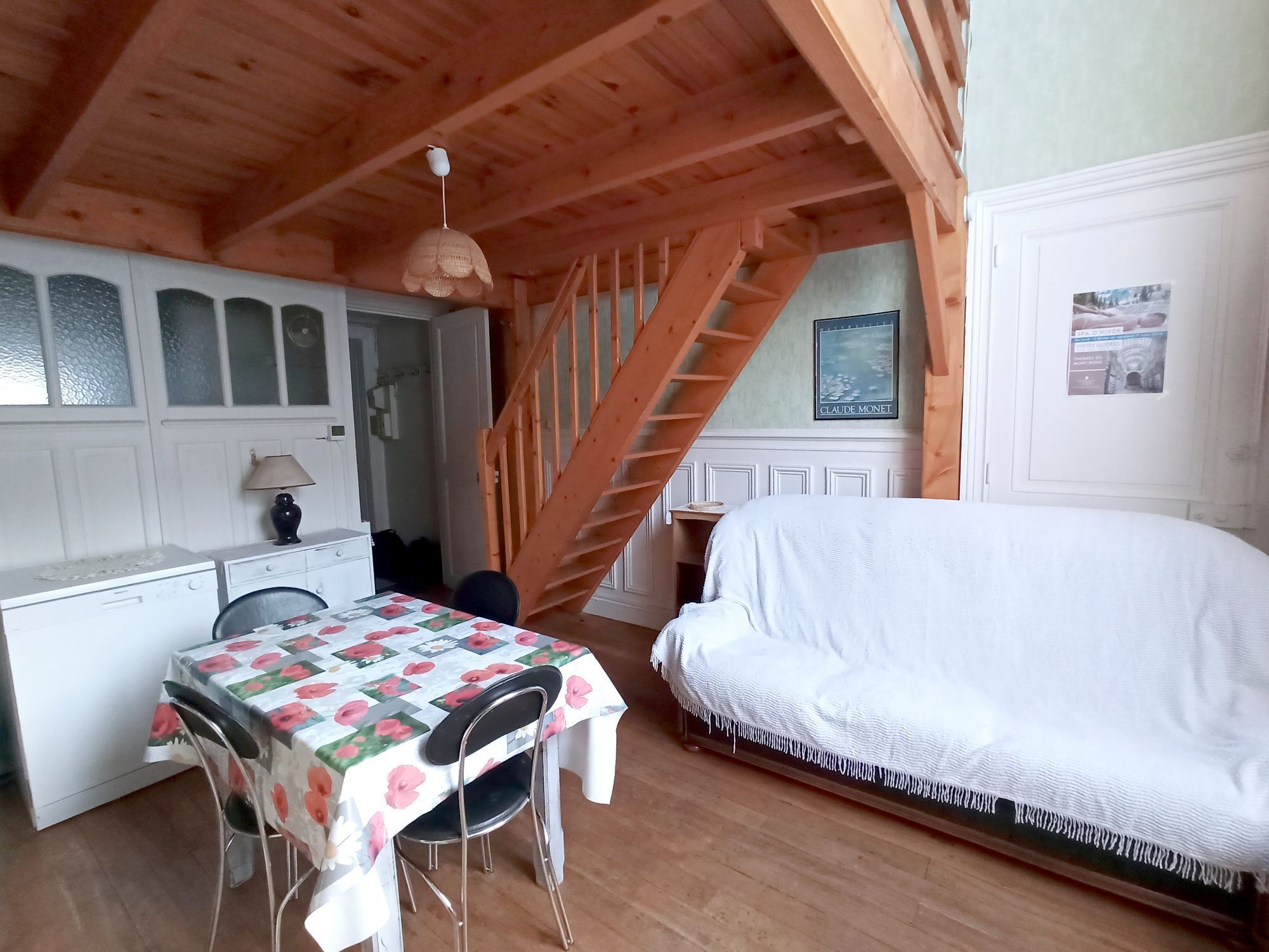 Een slaapkamer met een bed, een bureau en een stoel. Een trap leidt naar een hoger gelegen verdieping.