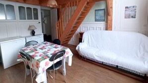 Een slaapkamer met een bed, een bureau en een stoel. Een trap leidt naar een hoger gelegen verdieping.