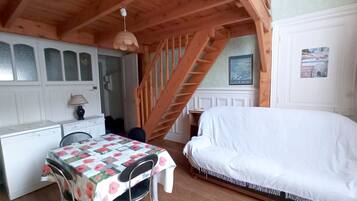 Een slaapkamer met een bed, een bureau en een stoel. Een trap leidt naar een hoger gelegen verdieping.