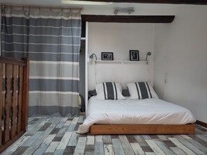 Ein Schlafzimmer mit einem Bett, Holzboden und einem Streifenmuster-Vorhang.