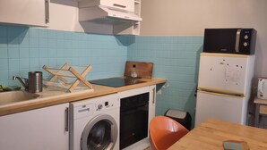 Eine kleine Küche mit Waschmaschine, Mikrowelle und Kühlschrank.