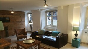 Una sala de estar con un sofá de cuero, una mesa de centro de madera y un tapete estampado.
