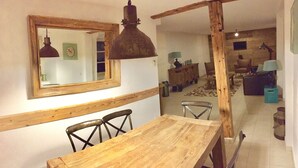 Un comedor con mesa y sillas de madera, una lámpara colgante y un espejo en la pared.