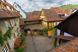 Eine enge Kopfsteinpflasterstraße in einem traditionellen europäischen Dorf mit Fachwerkhäusern und einem kleinen Innenhof.