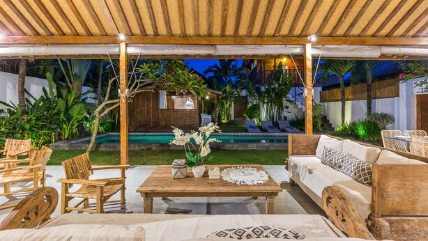 An outdoor patio area with wooden furniture, a pool, and tropical plants. - Villa Langka Harmony and calm in Seminyak Oberoi (Seminyak)
