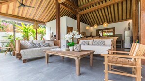 A spacious living area with a wooden ceiling, a sofa set, a coffee table, and a kitchen in the background. - Villa Langka Harmony and calm in Seminyak Oberoi (Seminyak)