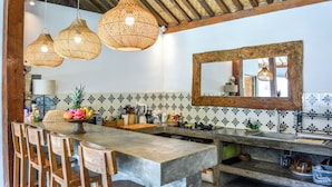 A kitchen with a large island, hanging wicker lights, and a tiled backsplash. - Villa Langka Harmony and calm in Seminyak Oberoi (Seminyak)