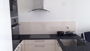 A modern kitchen with white cabinetry, a black countertop, and stainless steel appliances. - F1 1ST LINE EXCEPTIONAL SEA VIEW (Palavas-Les-Flots)