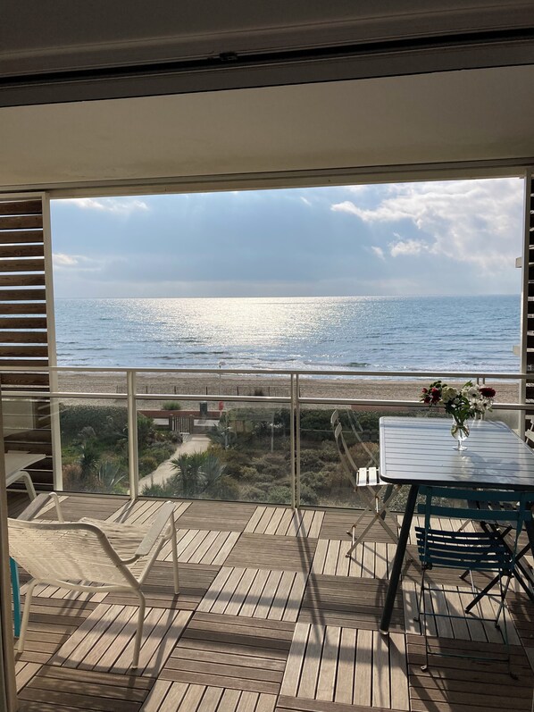 A balcony with a view of the sea, a table with flowers, and outdoor furniture. - F1 1ST LINE EXCEPTIONAL SEA VIEW (Palavas-Les-Flots)