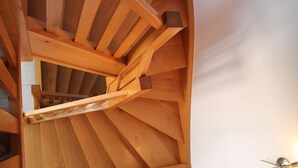 Un escalier en colimaçon en bois avec un espace central ouvert.