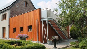 Un bâtiment moderne doté d’une façade en bois, d’un toit en briques et d’un escalier menant à un étage supérieur.
