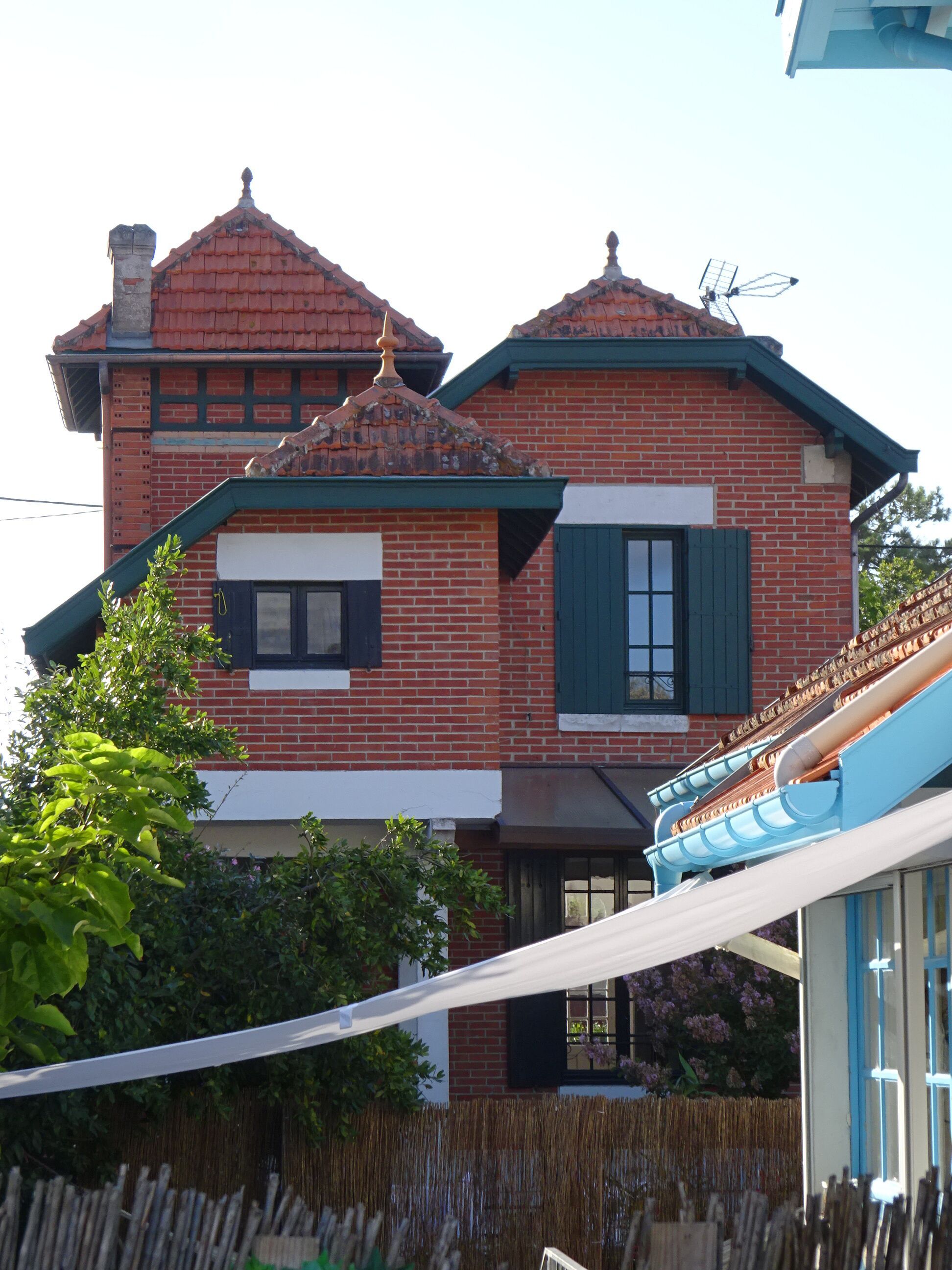 Une maison à deux étages, construite en briques, avec un toit à forte pente, une cheminée et une antenne parabolique.