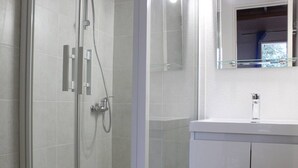 Une salle de bain moderne avec une douche à parois de verre, un lavabo blanc et un miroir au-dessus du lavabo.