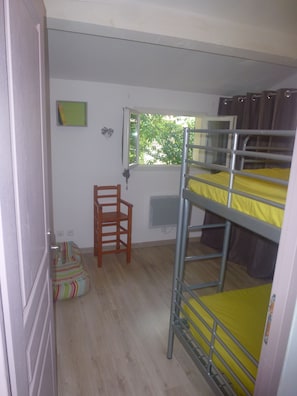 A dormitory room with bunk beds, a wooden chair, a window, and a radiator. - Gîte de Bizac river La Beaume 10mn walk near Ruoms (Saint-Alban-Auriolles)