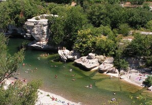 Un espace de baignade naturelle, avec des formations rocheuses et une eau claire, entouré d’une végétation luxuriante.