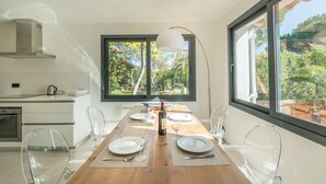 Eine moderne Küche mit Essbereich, großen Fenstern und Blick ins Grüne.