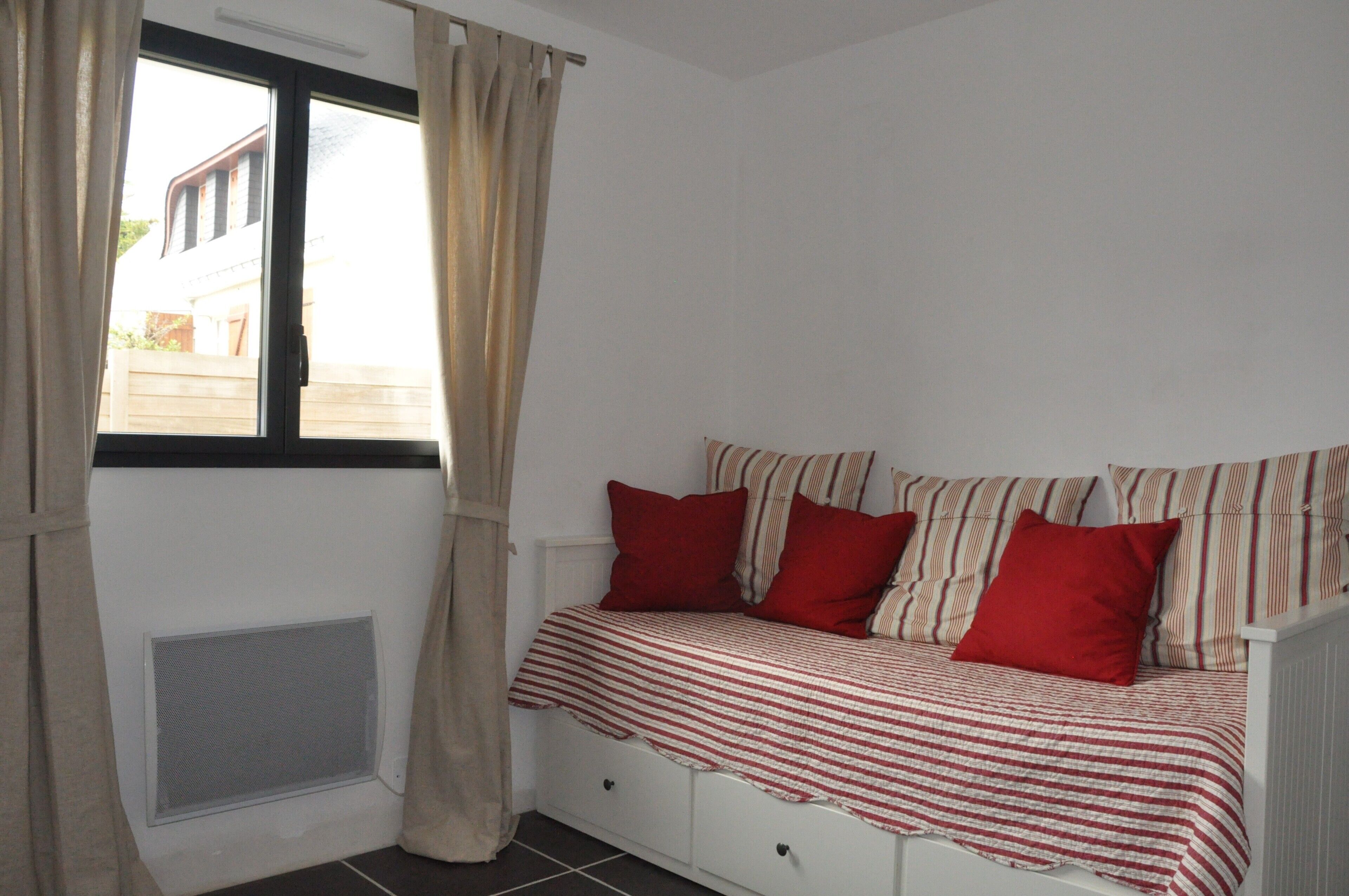 A bedroom with a bed, curtains, and a window.