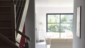 A modern interior with a staircase, a sofa, and a large window. -  Large luxury & calm villa (4 stars), close to beaches & small sea view (Saint-Gildas-De-Rhuys)