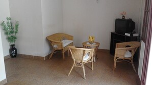 A small, enclosed room with wicker furniture, a tiled floor, a television, and a potted plant. - APARTMENT F3 bottom of villa to rent for holidays (ANSES D'ARLET)