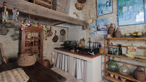 Una cocina rústica con estantes de madera, una estufa y diversos utensilios de cocina.