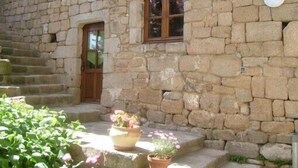 A stone building with a wooden door and window, steps leading to the entrance, and potted plants. - Quiet cottage with beautiful view (Chirols)