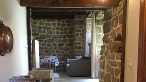 A stone-walled hallway leading to a living area with a sofa and a table. - Quiet cottage with beautiful view (Chirols)