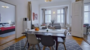 Ein modernes Wohnzimmer mit Essbereich, einer Couch, einem Couchtisch und einer Deckenleuchte.