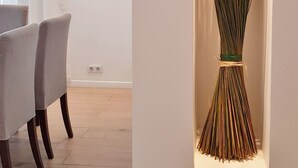 Un comedor moderno con una mesa, sillas, una lámpara fijada a la pared y una decoración floral.