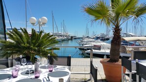 Un puerto deportivo con barcos amarrados, una mesa lista para comer y una palmera.