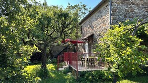A stone building with a balcony, surrounded by lush greenery and trees.