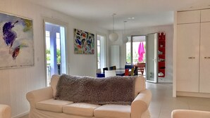 A modern living room with a white sofa, a red coffee table, and a painting on the wall. - Contemporary villa -Exceptional view of the dune-Private pool (Soorts-Hossegor)